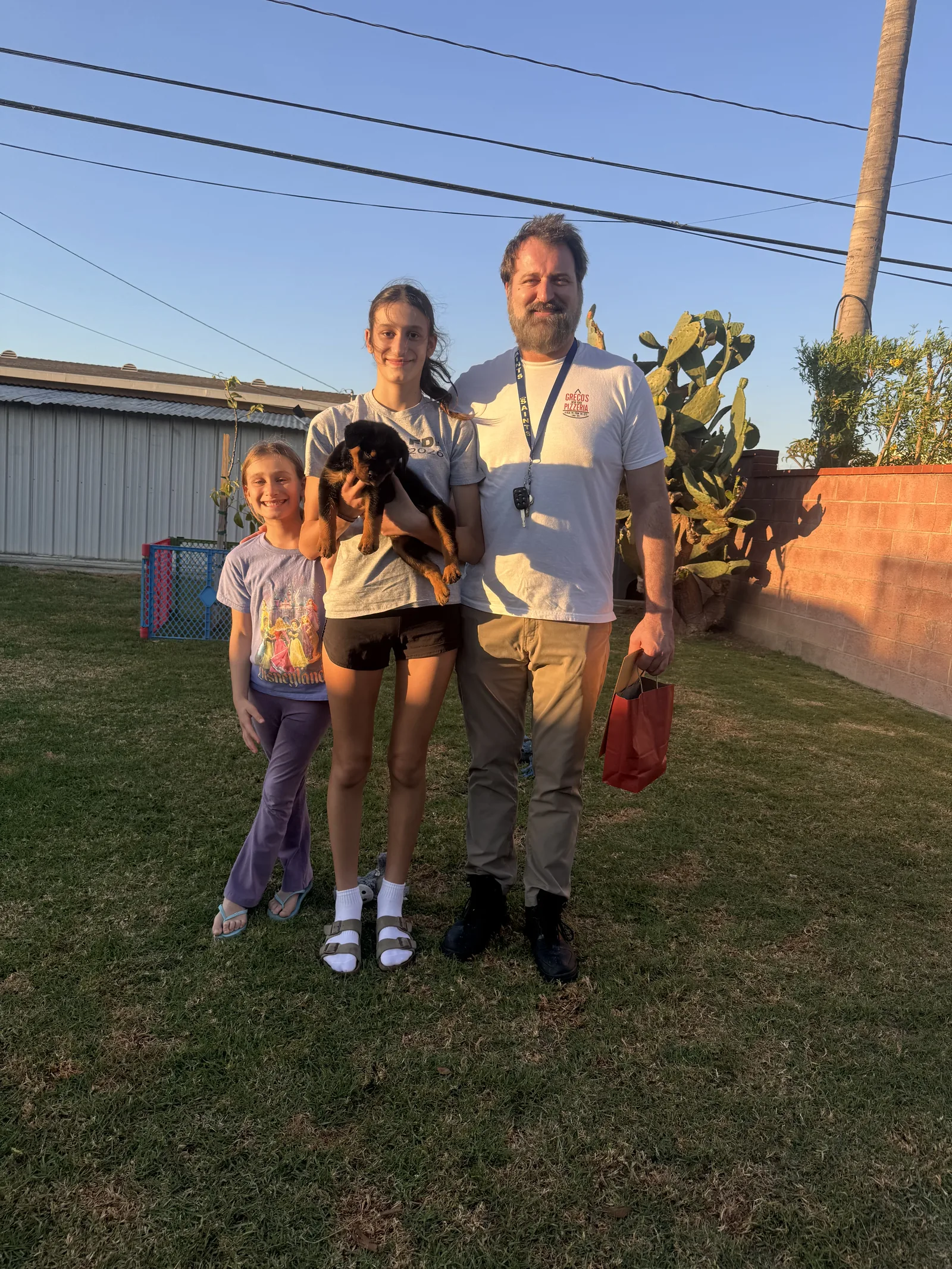 Lili's girl puppy held by her new family in their backyard on arrival day — from Lili and Monster's litter